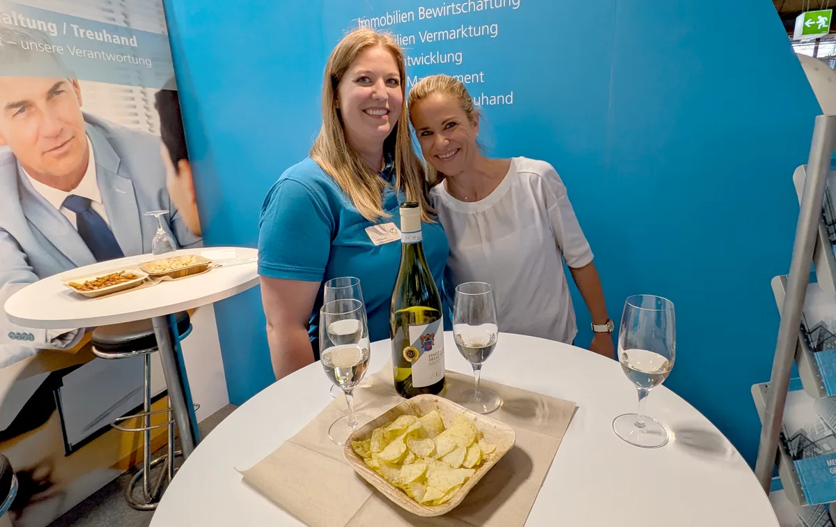 Zwei Frauen posieren für ein Foto, im Vordergrund Chips und Weisswein.